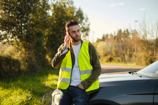istock Serious man talking to the phone sitting on a broken car 2101283246