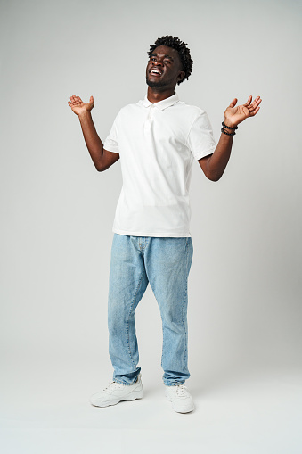 Young African Man Standing With Hands Raised in studio