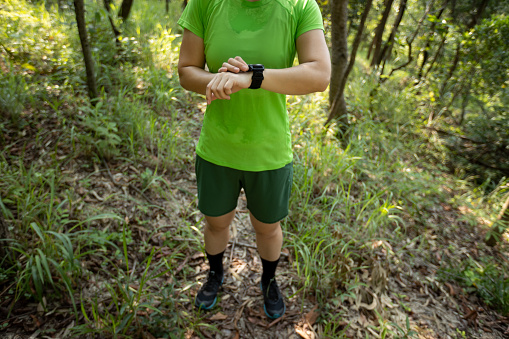 Woman trail runner set the sports watch in forest