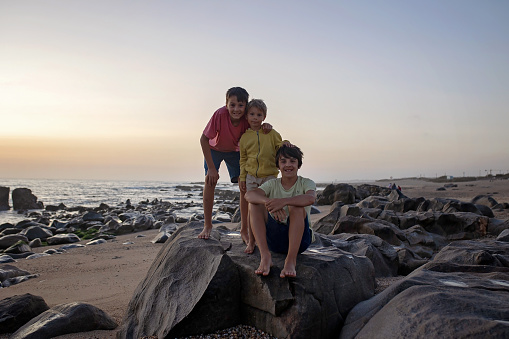Happy children, enjoying sunset over the ocean with their family, rocky beach in Portugal