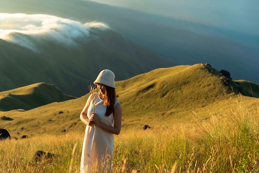 Happy young woman traveler relaxing and looking at the beautiful sunrise on the top of mountains, Travel lifestyle concept.Travel and summer Concept