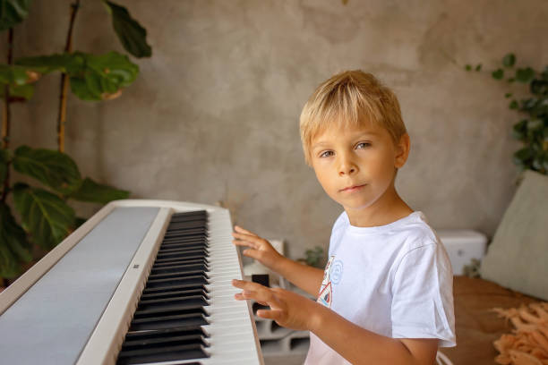 istock Child, blond boy, playing piano at home 2101305602
