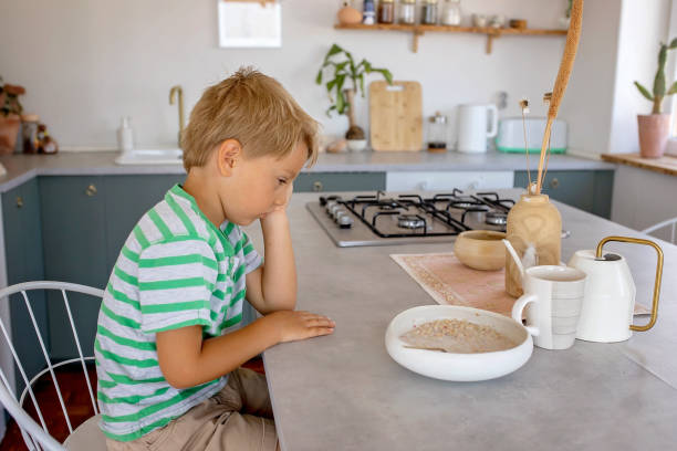 beautiful blond child, boy, refusing to eat cereal for breakfast at home in the morning - eating cereal student human mouth 뉴스 사진 이미지