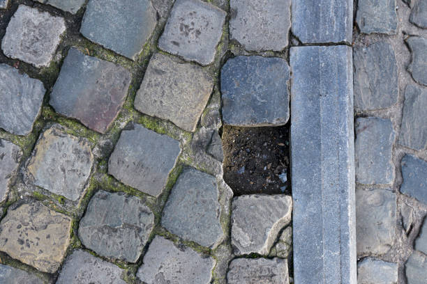 The stone in the pavement is missing. Hole in cobblestones from a lost stone