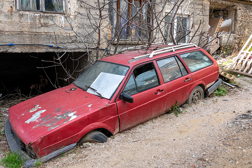 Tirana, Albania. 13 March 2024. Old abandoned car half buried in mud