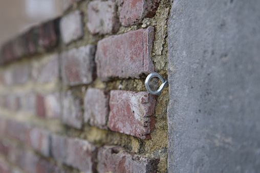 Metal screw with ring for fastening in concrete brick wall. Close-up