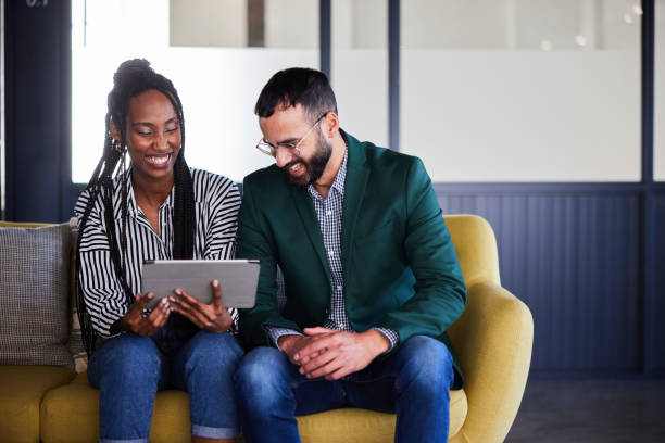 istock Two diverse young businesspeople laughing while using a tablet in an office 2101365235