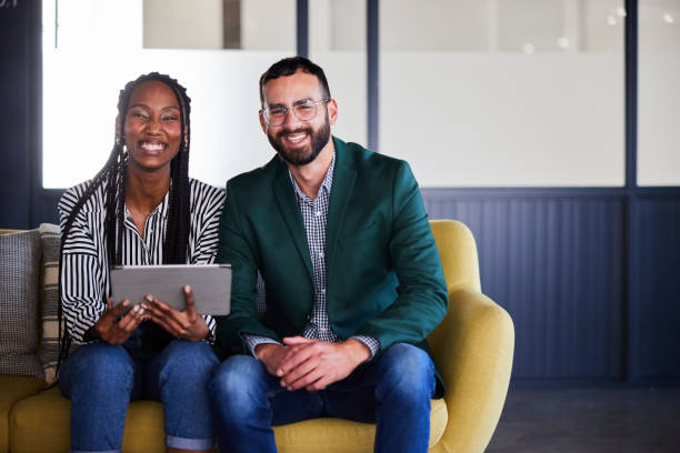 istock Two smiling young businesspeople using a tablet together on a sofa in an office 2101366284