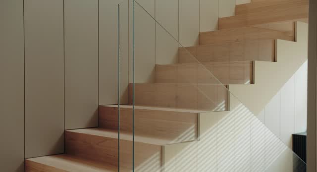 Wooden stairs with glass barrier in house with modern interior