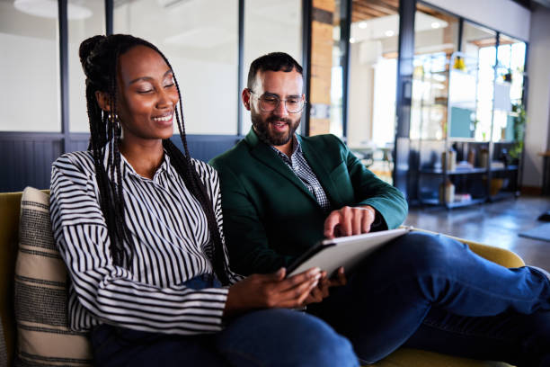 istock Two diverse young businesspeople using a tablet on a sofa in an office 2101391032