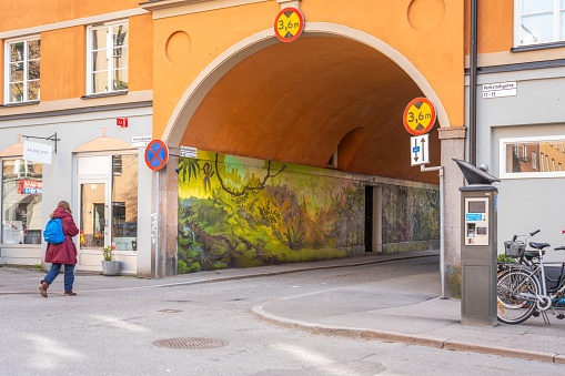 Stockholm, Sweden - April 16, 2022: Outdoor wall spray painted urban underpass at residential building with a woman approaching in Stockholm Sweden April 16, 2022.