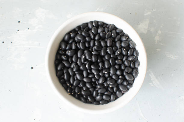 Raw black bens in a white bowl on a gray background. Concept of healthy eating. Vegetarian and vegan food. Horizontal orientation. Top view. stock photo