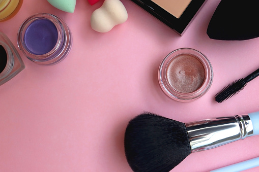 Various colorful beauty products on bright pink background. Top view.