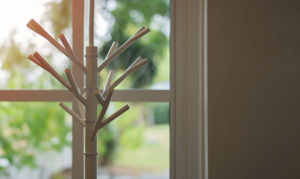 empty white wooden cloth hanger rack with beige wall background nearby the window - antique furniture old old fashioned imagens e fotografias de stock