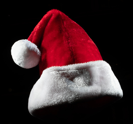 Hat usually worn by Santa Claus on Christmas Eve on a black background for use as a graphic element or icon.
