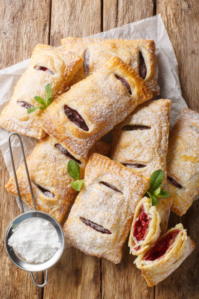 istock Cherry puff pastry with powdered sugar and mint close-up. Vertical top view 2101466296