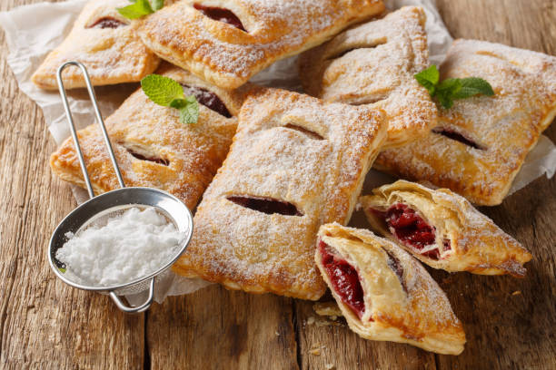 istock Baked puff cherry pies with powdered sugar and mint close-up. Horizontal 2101467428