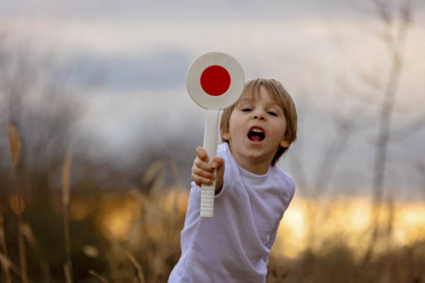 Child, boy, holding start/stop policeman control traffic paddle, wanting to become a policeman in the future