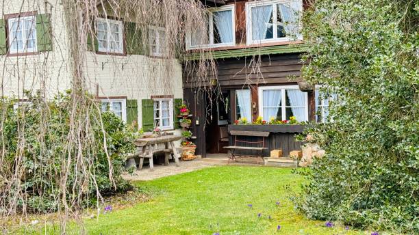 Oberstdorf, Germany - March, 15th - 2024: Typical garden, bench and a wooden house facade.