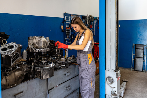 A Female Car Mechanic is Checking the Car Condition and Engine with Mechanic Tools in a Car Service.