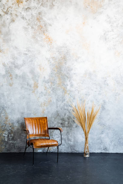 istock A brown leather chair contrasts against a concrete wall in a minimalist setting 2101562549