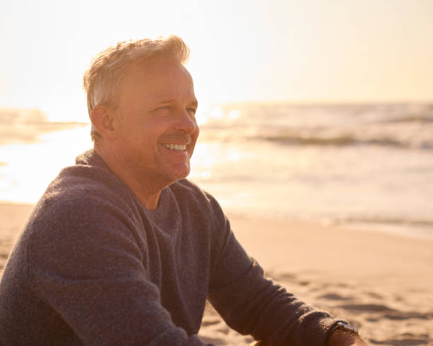 istock Retired Senior Man On Vacation Sitting On Beach Shoreline Watching Sunrise 2101567089
