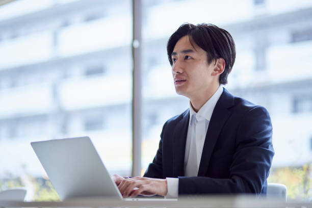 istock A young Japanese businessman in a suit working on a computer in the office 2101583659