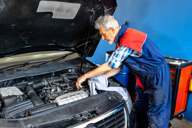 an experienced car mechanic is checking car oil level in a car service. - old men car oil стоковые фото и изображения