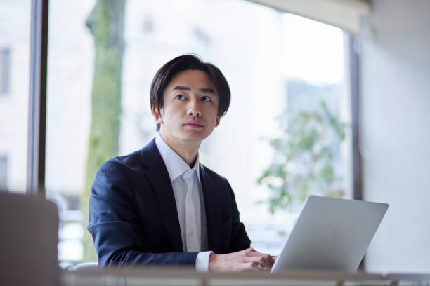 istock A young Japanese businessman in a suit working on a computer in the office 2101584169