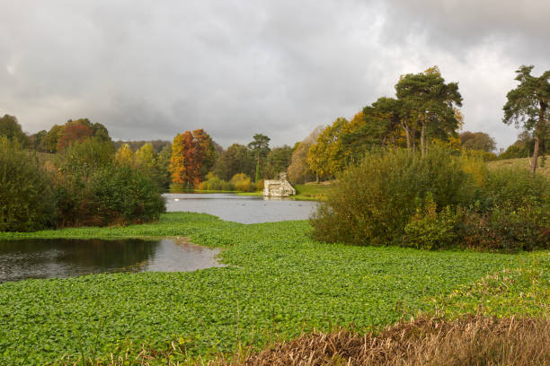 English country house grounds. Lake with boathouse.