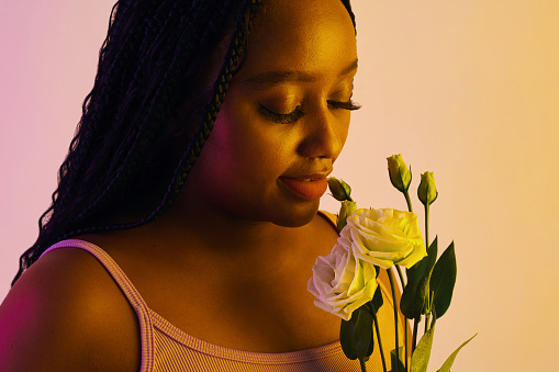 Cropped image of Black woman enjoying smell of fresh flowers