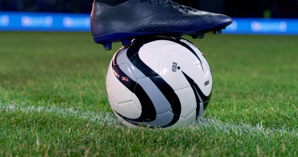 Close-up of football boot on football during match.