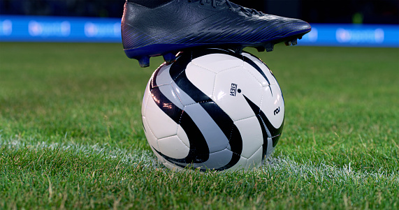 Close-up of football boot on football during match.