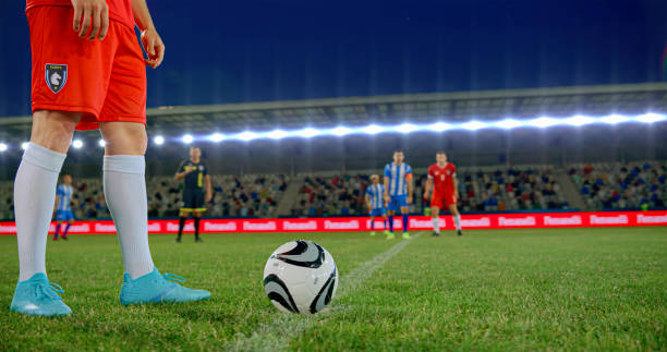 Male football player standing for ready to kick of ball on pitch during beginning of match.