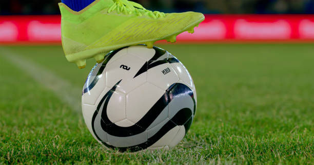 Close-up of football boot on football during match.