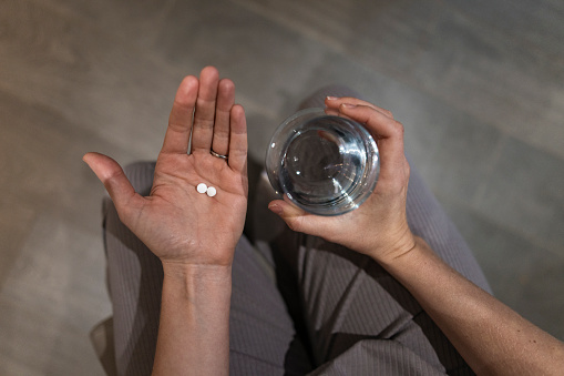A high-angle point of view of an unrecognisable woman and her hand holding vitamins and medication to be taken as part of a fertility treatment she is going through with the support of her wife.