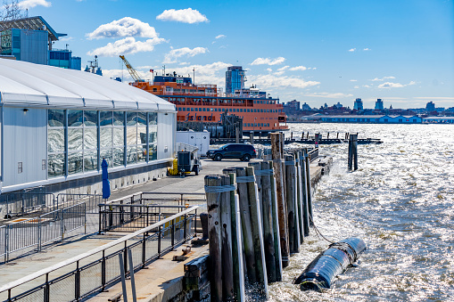 Hudson river, New York, USA - March, 2024.  Liberty island Ferry terminal at Battery park with the  Staten island Ferry in the background on the Hudson River.