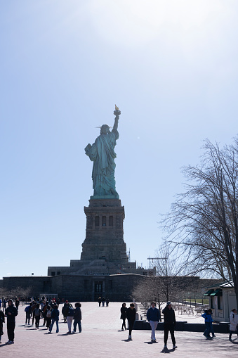 Liberty Island, New York, USA - March, 2024.  Statue of Liberty on Liberty island with tourists in the foreground near the Statue of Liberty museum.