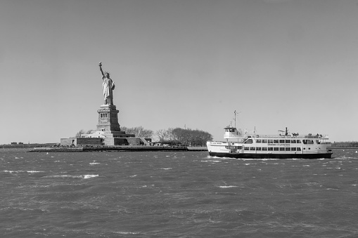 Liberty island, New York, USA - March, 2024. Statue of Liberty on Liberty island behind Liberty ferry in Hudson River.