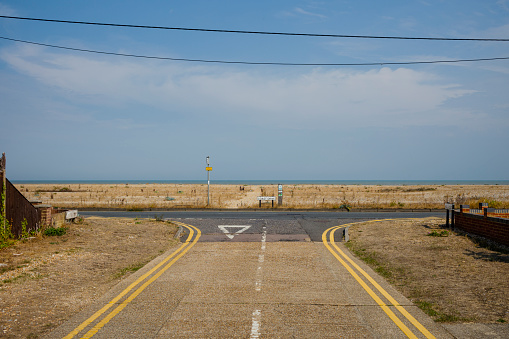 A road junction with no cars and a view of a horizon over the English Channel on a sunny day.
