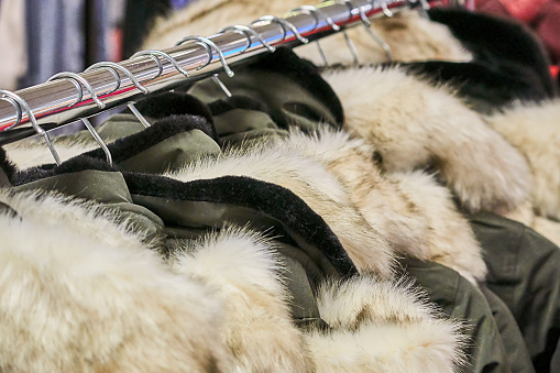 green coats with fur collars on the clothes rack