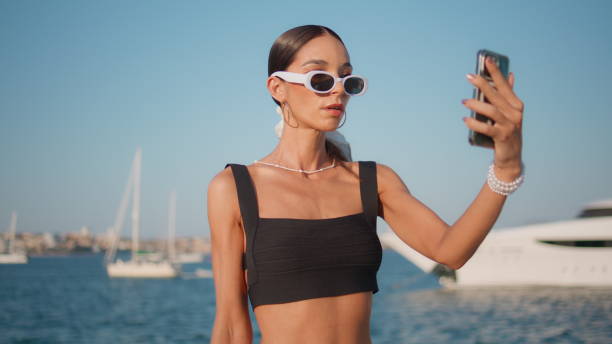 istock Luxurious girl making selfie on cellphone posing at ocean shore close up. 2101674513