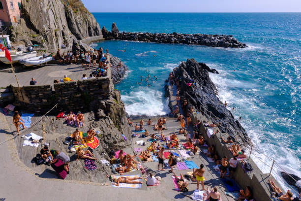 Manarola, IT - 26 July 2023: People sunbathing at Manarola Harbor