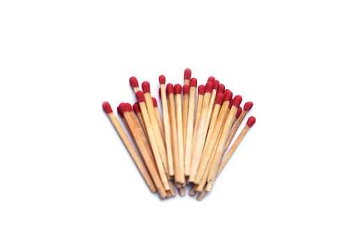 High angle closeup view of a white box of matches and several loose matches scattered on a weathered rustic old wooden bench.