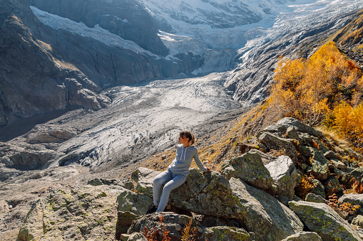 Woman in the mountains. Mountain with glacier and tourist sitting on stones