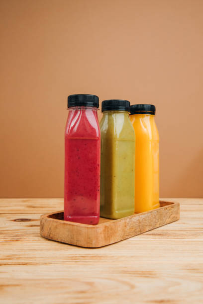 istock Fruit and vegetable smoothies in transparent plastic bottles. Green, red, orange smoothies on a brown and wooden background 2101720978