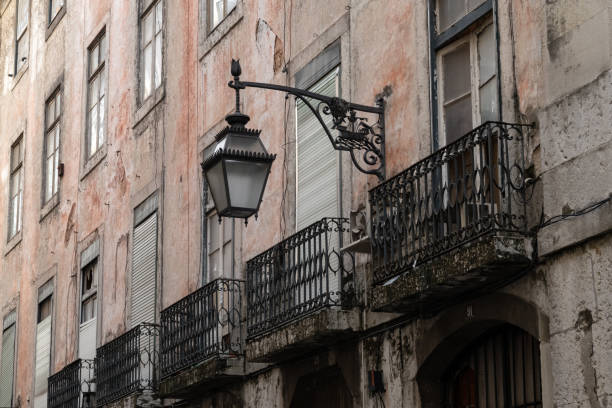 Classic street light in wrought iron hanging off the dilapidated wall of an abandoned apartment building in central neightbourhood in Lisbon in Portugal