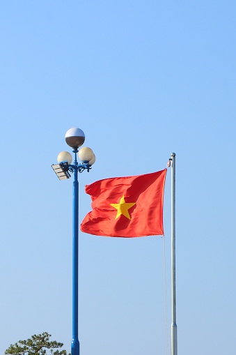 The Vietnamese flag flutters in the wind. Flag on the metal flagpole.