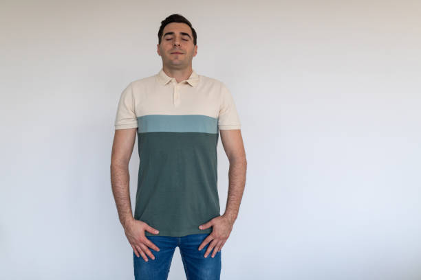 Portrait of a mid adult Caucasian man meditating in front of a white wall in an apartment