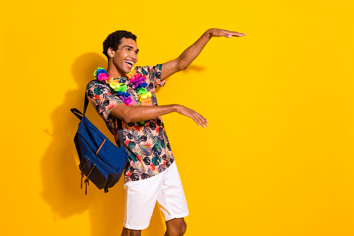 Photo of boogie woogie party guy t shirt has chill vibe dance in hawaiian necklace and backpack isolated over yellow color background.